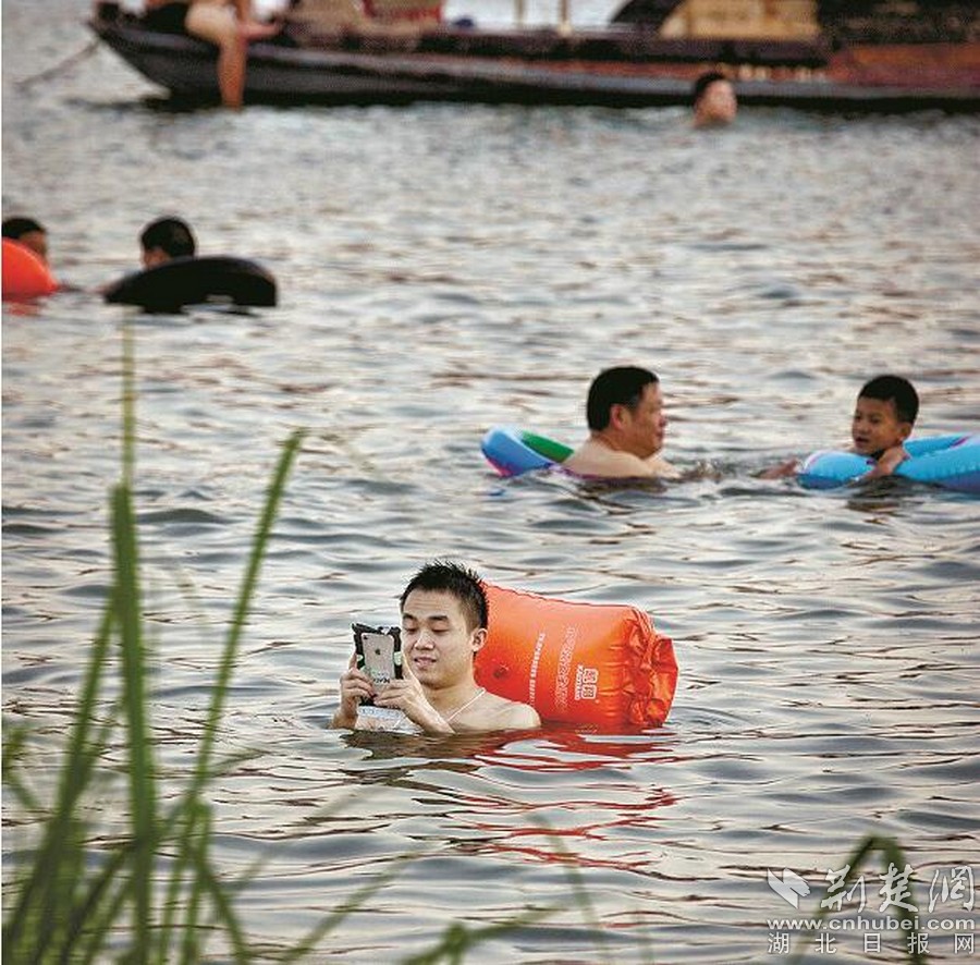 在水中,有人在看電影,有人發朋友圈,有人聊視頻,有人玩自拍……他們的共同特點只有一個:低頭,緊盯著手機屏幕,甚至很少變換姿勢。對于這份“執著”,有人表示無法理解,有人表示“挺有趣”。而給手機套上“防水神器”的低頭族們,則會認真告訴你,“我需要使用手機”。圖為:漢江里水流洶涌,依舊有人“刷屏”