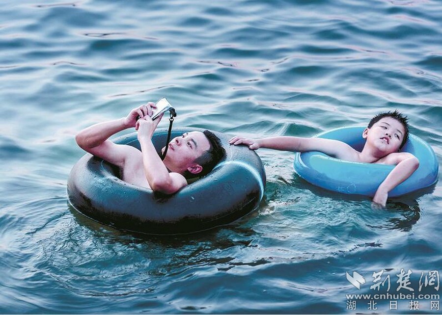 有時候,分不清人是主角,還是手機是主角。不過各場館的管理人員仍給出一條提醒:水上游玩項目需要更多的安全意識,帶孩子的家長更該注意,不要為了低頭看手機忽視了照顧及保護好自己的孩子。畢竟手機世界再美,也不如現實世界重要。 圖為:東湖里,一名“低頭族”正在專心玩手機